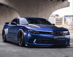 a blue chevrolet camaro is parked under a bridge