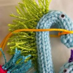 a crocheted blue bird with yellow beak and tail, sitting on a white surface