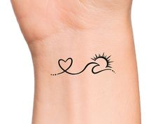 a small tattoo on the wrist of a woman's arm with sun and heart