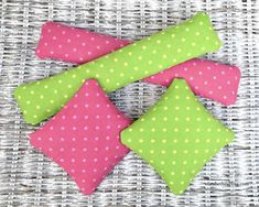 four pink and green polka dot pillows on a wicker surface