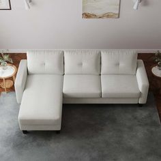 a white sectional sofa sitting on top of a gray rug