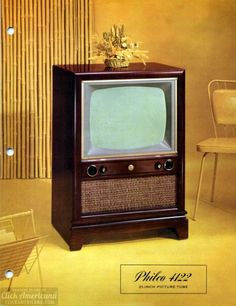 an old tv sitting on top of a wooden stand in front of a chair and table