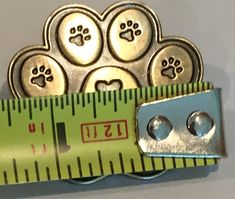 there is a measuring tape that has some dog paw prints on it, and two silver buttons