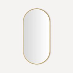 an oval mirror with a gold frame on a white wall, in the shape of a rectangle