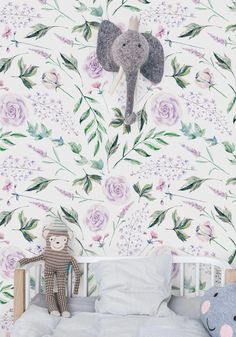 an elephant is hanging on the wall above a crib with stuffed animals in front of it