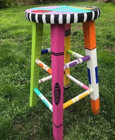 a colorful stool made out of crayons in the grass with measuring tape on it