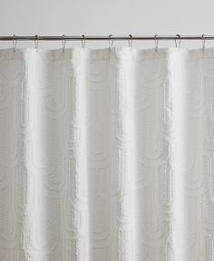 a white shower curtain hanging on a metal rod