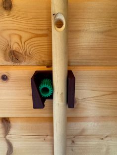 a wooden wall with a green object in the center and a baseball bat hanging from it