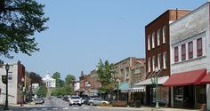 an empty street with cars parked on both sides and buildings in the backround