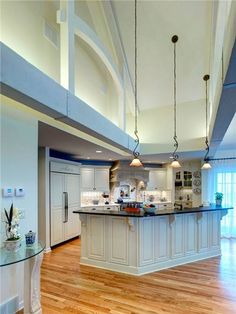 a large kitchen with white cabinets and wooden floors