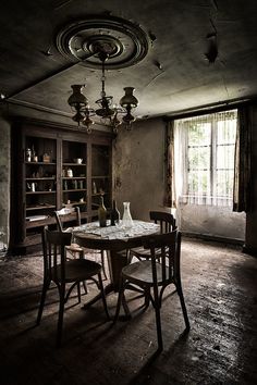 an old dining room table and chairs in the middle of a dark room with open bookcases