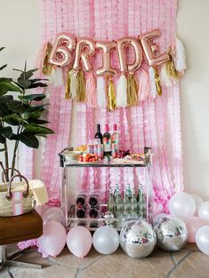 a pink and gold bridal party with balloons, streamers, confetti, champagne bottles