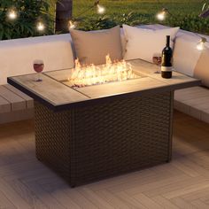 an outdoor fire pit sitting on top of a wooden floor next to pillows and wine bottles