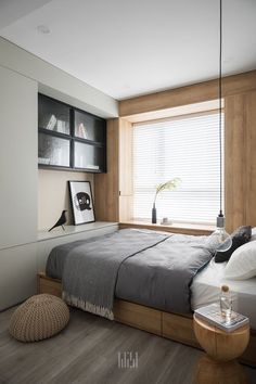 a bed sitting in a bedroom under a window next to a wooden floor and white walls