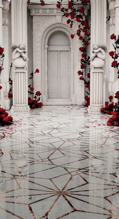 a white building with red flowers on the ground in front of it and a door