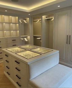 an empty walk in closet with white drawers and glass shelves on the wall above it