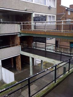 an empty parking lot in front of some buildings with balconies on the second floor