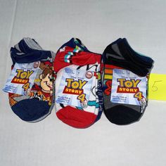 three pairs of toddler's toy story socks on a white surface with a yellow tag