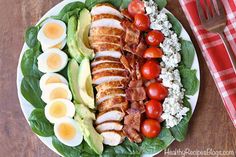 a plate with eggs, bacon, avocado, tomatoes and other food on it