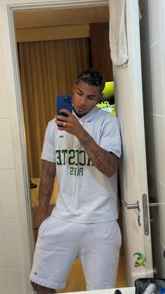 a man taking a selfie in his bathroom mirror while wearing white shorts and a t - shirt