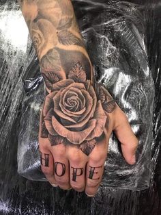 a person's hand with a rose on it and the word hope written in black ink