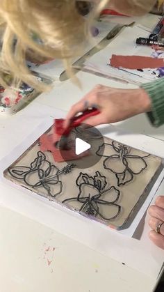 a woman cutting up a piece of art with scissors