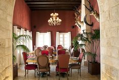 a dining room with red chairs and tables in front of a stone archway that leads to another room