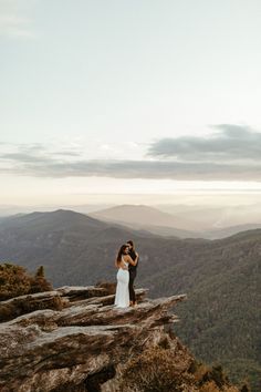 a bride and groom standing on top of a mountain