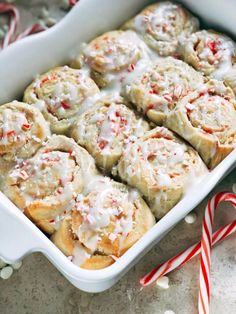 a white dish filled with cinnamon rolls and candy canes