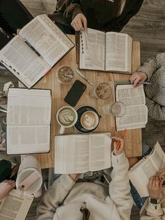 people sitting at a table with open books and papers in front of them on top of each other