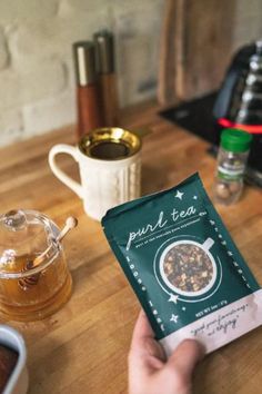 a person holding up a bag of tea on a table