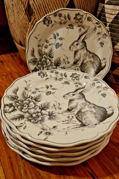 a stack of plates sitting on top of a wooden table next to wicker baskets