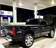 a black truck is parked at a gas station