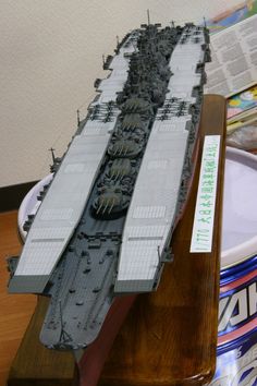 a model battleship sitting on top of a wooden table next to a can of soda