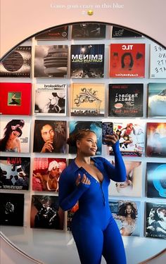 a woman standing in front of a wall with various records on it