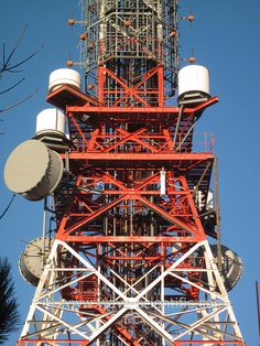 the top of a tower with multiple cell towers on it's sides and two satellite dishes attached to them