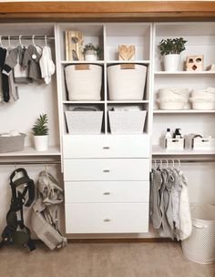 an organized closet with white shelves and baskets