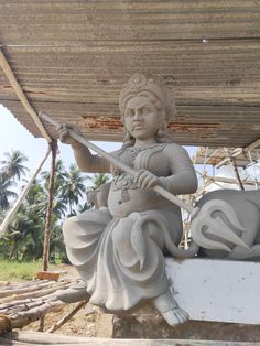 a statue of a woman with a violin and an elephant in front of her, under a wooden structure