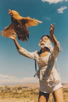 a woman holding up a chicken in the air