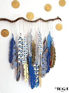 a wind chime with feathers hanging from it's side on a white wall