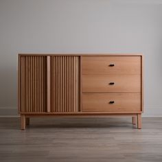 a wooden dresser sitting on top of a hard wood floor next to a white wall