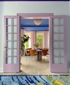 an open door leading to a dining room with blue walls and purple trim on the doors