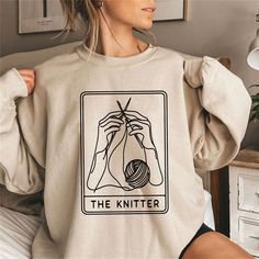 Cozy up in our 'The Knitter' Sweatshirt, the perfect blend of comfort and creativity for those who adore the art of knitting. Inspired by the timeless Tarot cards, this sweatshirt is a trendy tribute to your knitter's pride. Ideal for both crafting at home or showcasing your hobby out and about, it's a staple piece for any knitting enthusiast. The soft fabric ensures warmth and ease, while the unique design speaks to your artistic side. A wonderful gift for knitters, this sweatshirt is a snug an Funny Knitting, Knitting Shirt, Knitting Humor, The Knitter, 8bit Art, Knitting Gift, Knit Shirt, Sweatshirt Designs, Staple Pieces