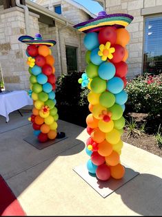 two tall colorful balloons are in front of a house with a mexican hat on top