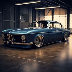 an old blue car is parked in a large room with dark walls and flooring