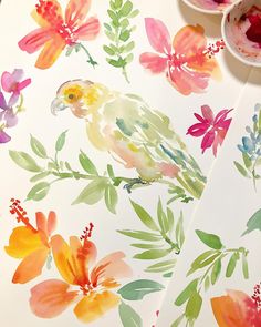 watercolor flowers and birds painted on white paper with paintbrushes next to them