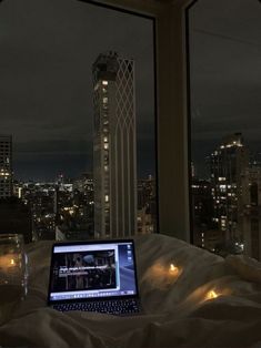 an open laptop computer sitting on top of a bed in front of a large window