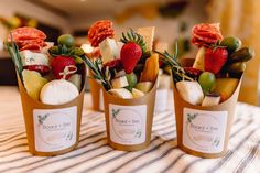 three small cups filled with different types of fruits and cheese on top of a table