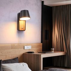 a room with a bed, desk and lamp on the wall next to a window