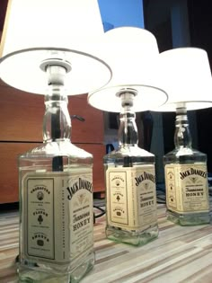 three empty bottles sitting on top of a table next to a lamp and some lightshades